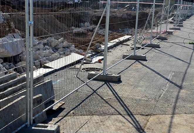 construction workers installing temporary fence panels for a job site perimeter